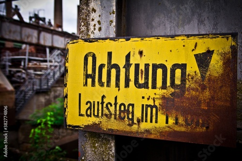 UNESCO World Heritage site: Volklingen Ironworks, Germany. Battered, rasty, yellow sign on the wall: Achtung! 