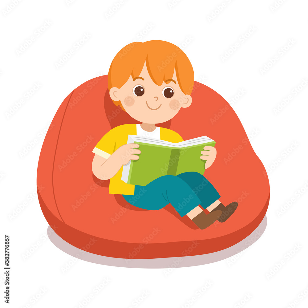Happy boy reading a book sitting on sofa in room.