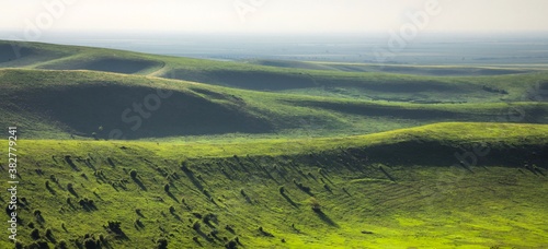 Green valley and hills with bushes in the range of mountains in Ingushetia, Russia. Foggy horizon in the sunrise.