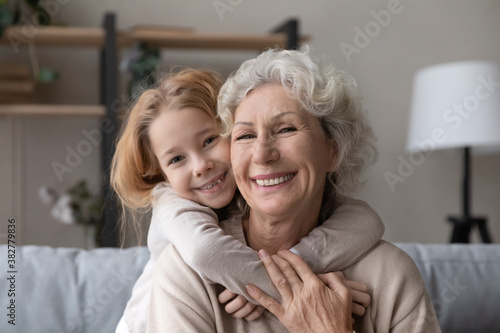 Cuadro en lienzo Head shot portrait smiling mature grandmother piggy backing little granddaughter