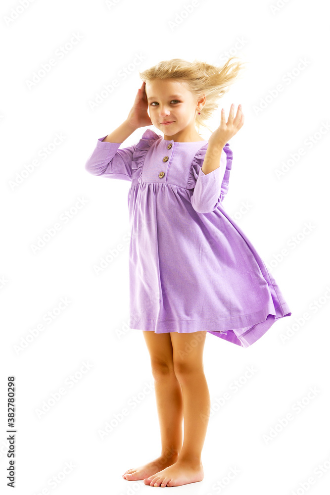 A beautiful little girl stands in the wind, her hair and clothes are developing greatly. The concept of style and fashion.