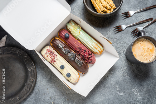 Quadro su tela Set of different eclair cakes packed in cardboard box on grey background