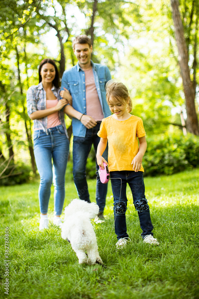Happy family with cute bichon dog in the park Happy family with cute bichon dog in the park