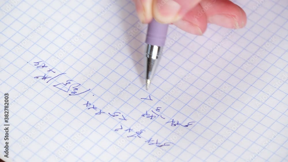 The hand holds a pen and writes a mathematical formula in a notebook. Solution of equation. The concept of education and research.