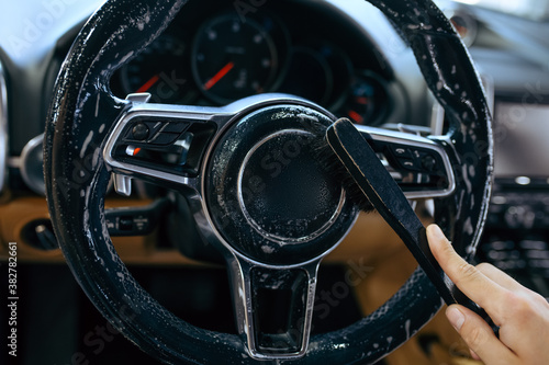 Worker wipes car steering wheel, detailing