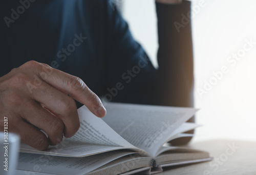 Close up of a man reading a book on table