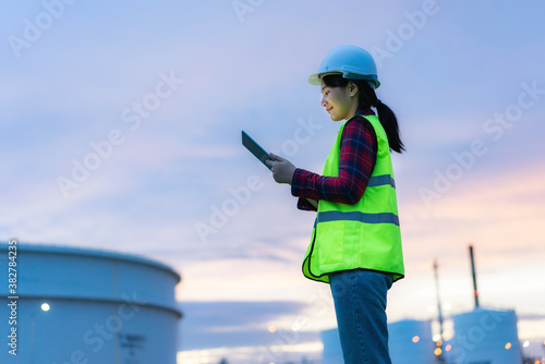 Fotografija Asian woman petrochemical engineer working at night with digital tablet Inside oil and gas refinery plant industry factory at night for inspector safety quality control