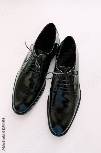 Black glossy men's classic derby shoes on a white background.