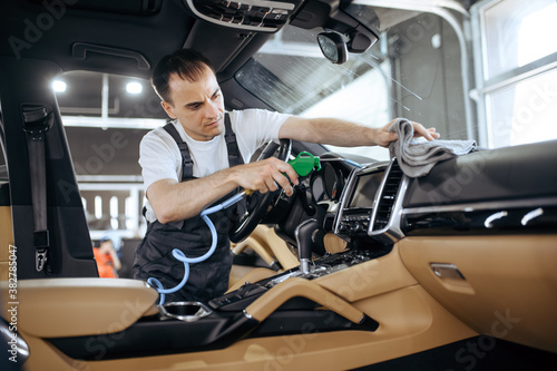 Worker with air gun cleans car air duct grating