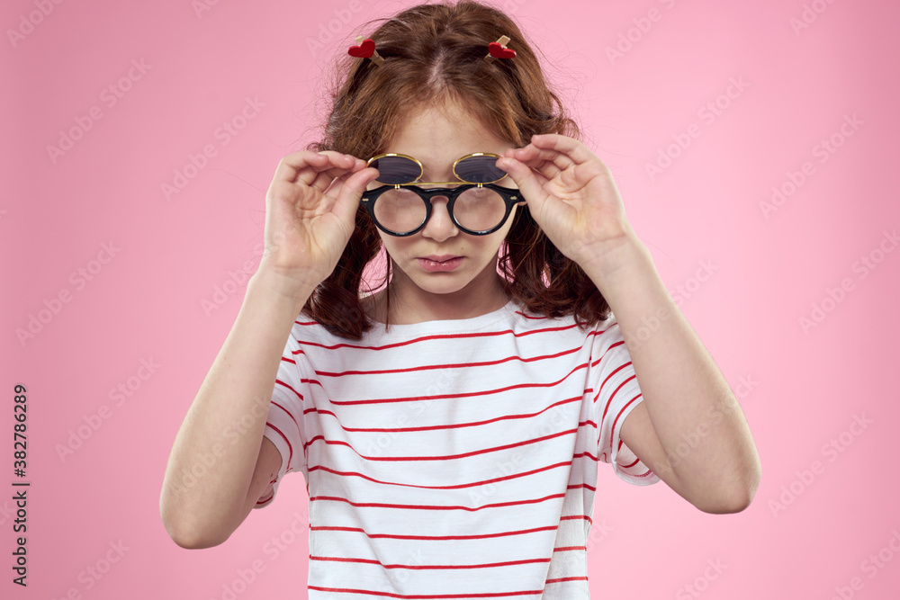 Cheerful girl with pigtails sunglasses striped t-shirt lifestyle pink background Cheerful girl with pigtails sunglasses striped t-shirt lifestyle pink background