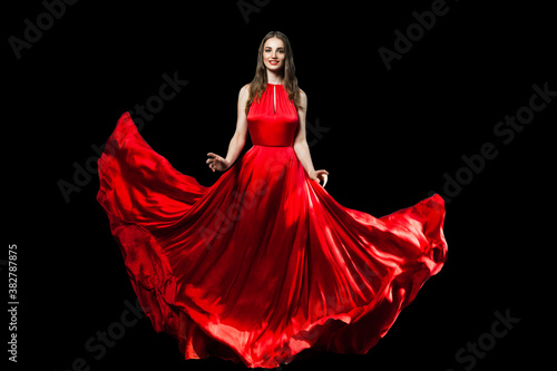 Beautiful fashionable woman wearing red silky dress isolated on black background