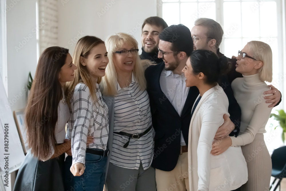 Excited diverse employees businesspeople have fun engaged in group teambuilding activity in office. Smiling overjoyed colleagues coworkers hug embrace show unity and support. Cooperation concept. Excited diverse employees businesspeople have fun engaged in group teambuilding activity in office. Smiling overjoyed colleagues coworkers hug embrace show unity and support. Cooperation concept.