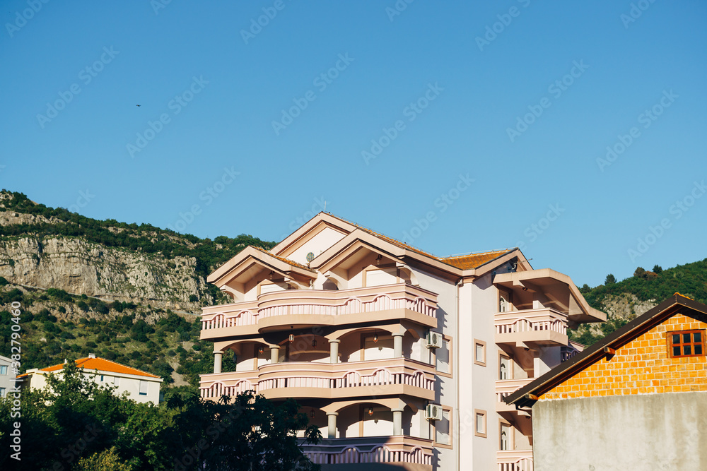 A hotel with large balconies among the mountains against a blue sky.