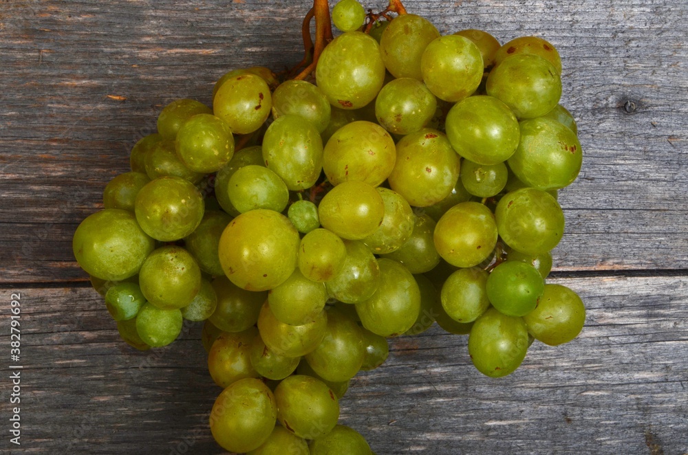 A large bunch of yellow green grapes on a wooden board background. ripe juicy green grapes, copy space A large bunch of yellow green grapes on a wooden board background. ripe juicy green grapes, copy space