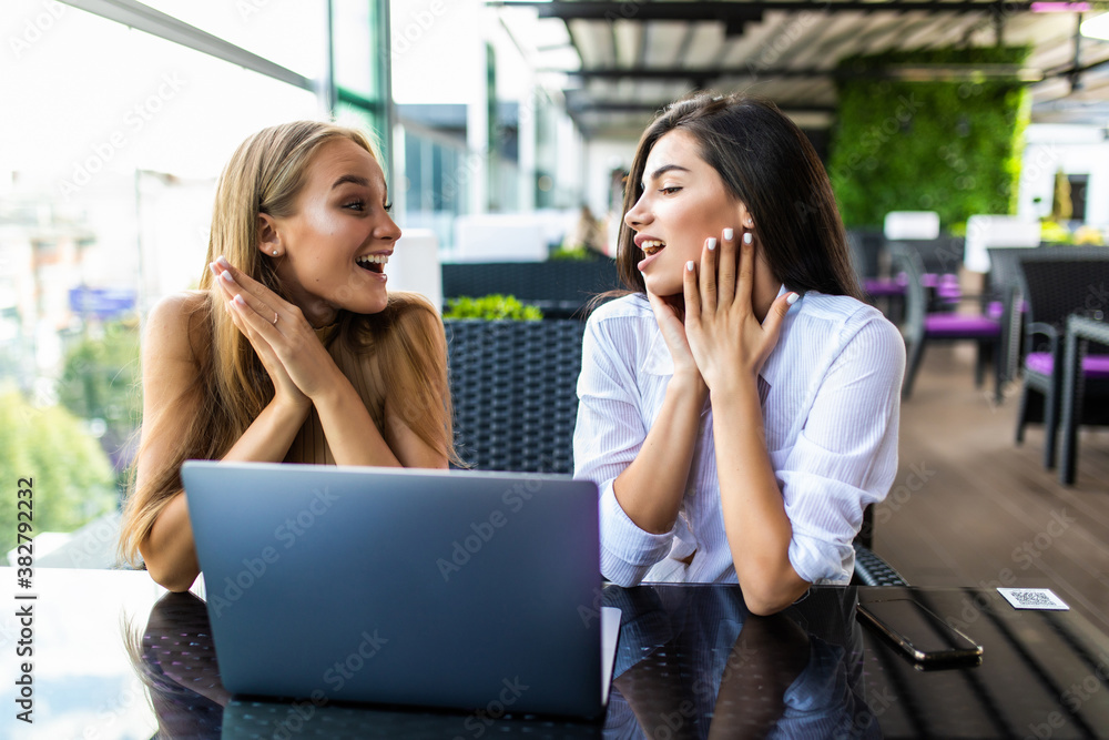 Two women using laptop in a coffee shop Two women using laptop in a coffee shop