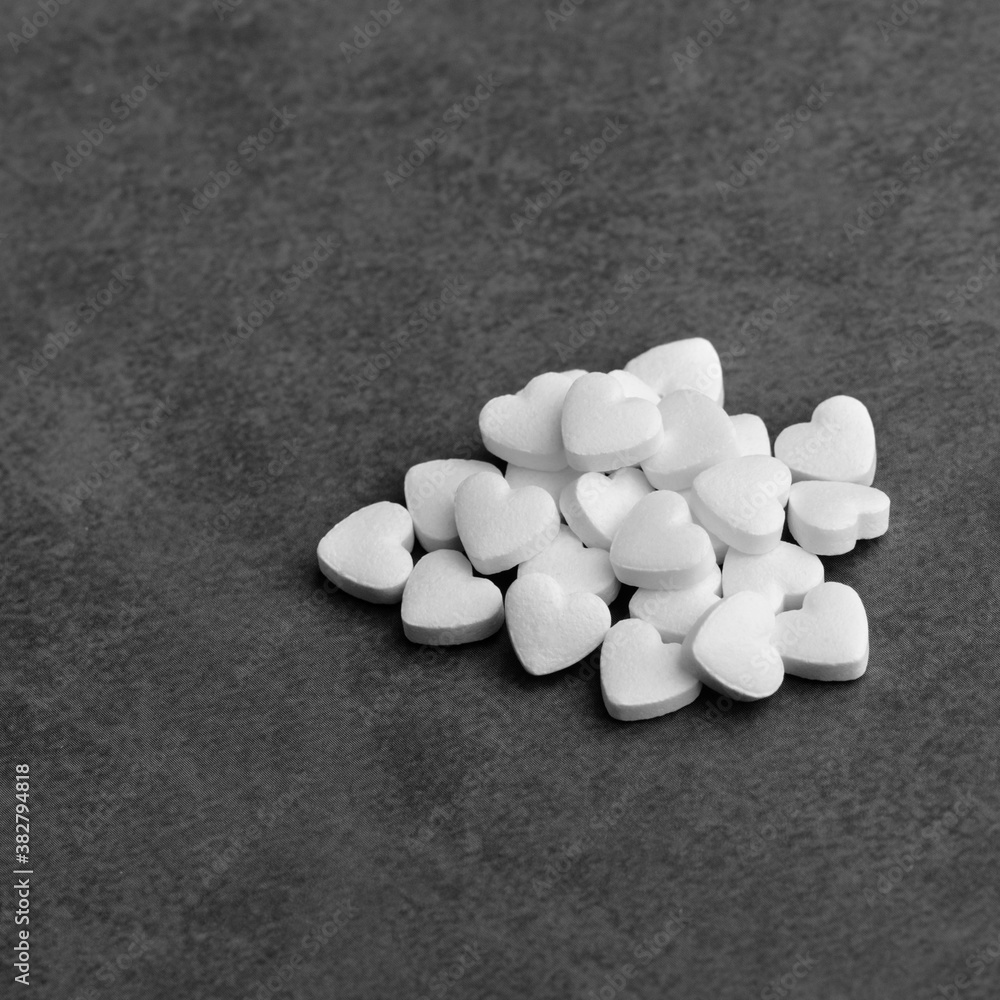 White medical pills in the form of hearts on a gray background. White medical pills in the form of hearts on a gray background.