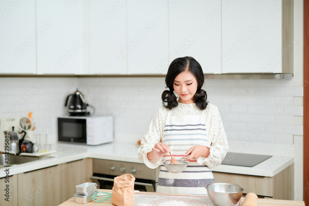 Pretty asian woman in a professional kitchen prepares the dough with flour Pretty asian woman in a professional kitchen prepares the dough with flour
