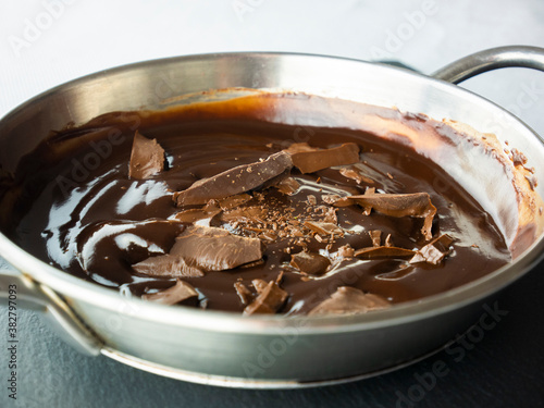 Temper the chocolate in a saucepan. Pieces of chocolate. Preparing cocoa mousse. Cooking sweets. Top view. Still life food.