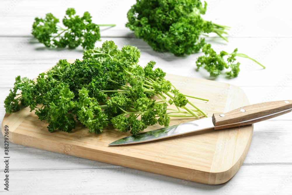 Fresh curly parsley, cutting board and knife on white wooden table Fresh curly parsley, cutting board and knife on white wooden table