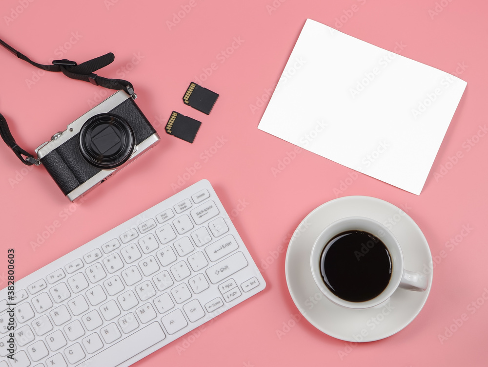 flat lay of camera, memory card, computer keyboard, coffee cup and blank photo paper on pink background. flat lay of camera, memory card, computer keyboard, coffee cup and blank photo paper on pink background.