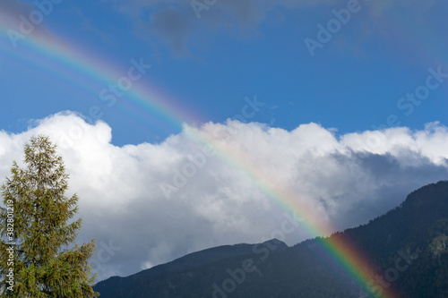 rainbow in mountain landscape with blue sky and white clouds