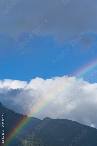 rainbow in mountain landscape with blue sky and white clouds