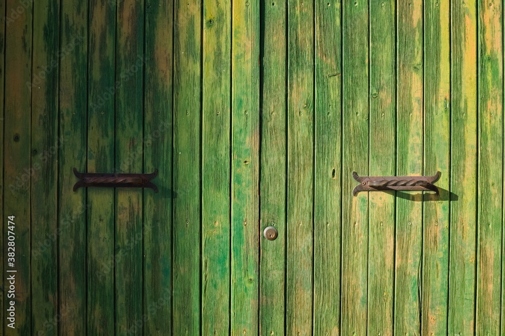 Old green wooden door with rusty handles in a small village (Corinaldo, Marche, Italy, Europe) Old green wooden door with rusty handles in a small village (Corinaldo, Marche, Italy, Europe)