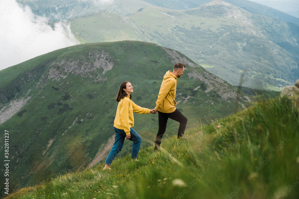 Obraz premium Love in the mountains. Happy couple in love walking in the mountains holding hands and enjoying the beautiful scenery