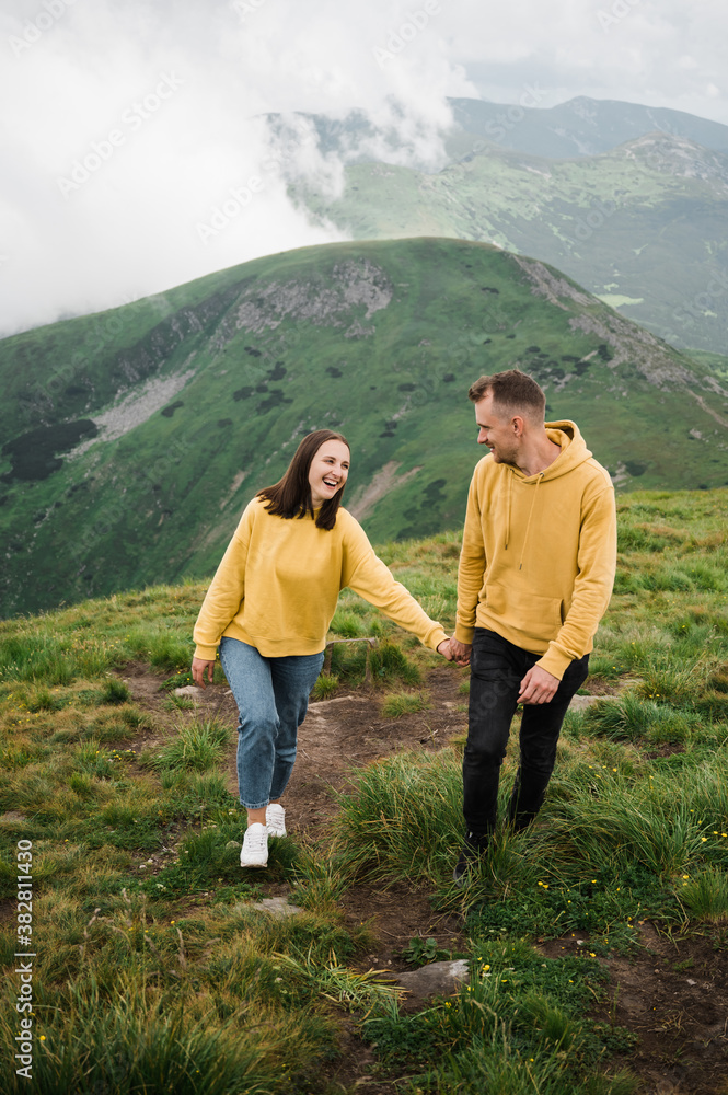 A couple in love is hiking holding hands on the top of mountains and enjoying with a scenic view around them