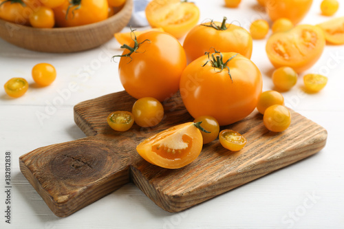 Ripe yellow tomatoes on white wooden table