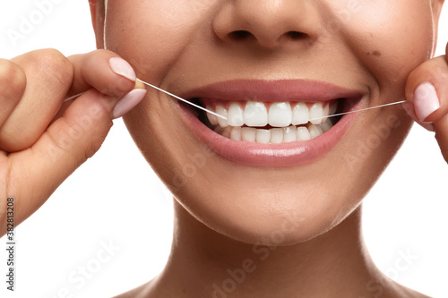 Young woman flossing her teeth on white background, closeup. Cosmetic dentistry