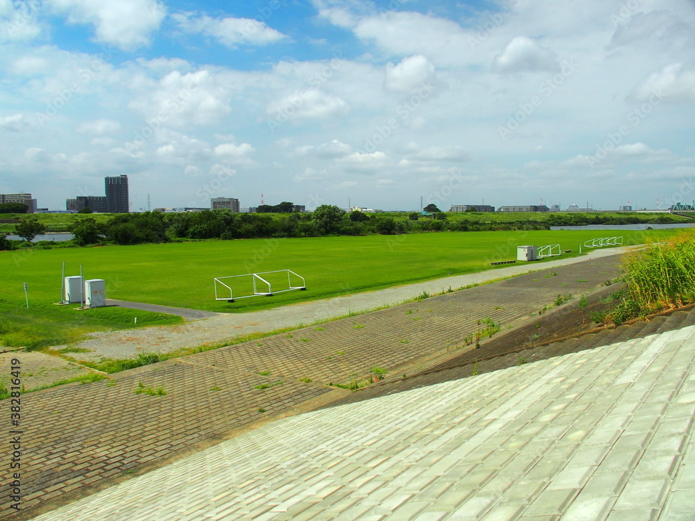 Obraz premium 晩夏の江戸川土手から見る護岸と河川敷のグラウンド風景