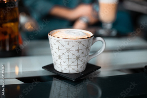 Hot coffee in a large ceramic cup on a glass table in a cafe