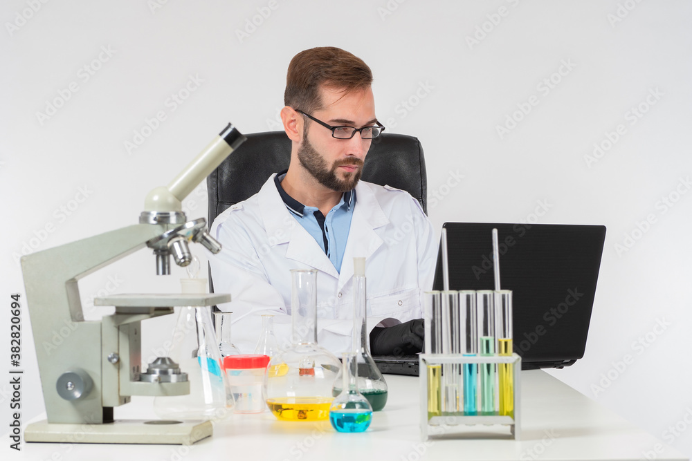 The chemist enters the results of the experiment into the computer. A man works on a laptop in the chemical laboratory. The course of the experiment with chemical liquids. The chemist enters the results of the experiment into the computer. A man works on a laptop in the chemical laboratory. The course of the experiment with chemical liquids.