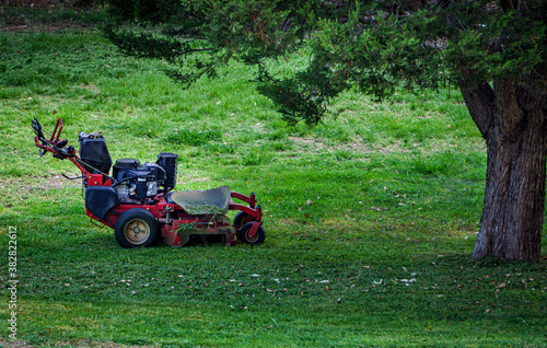 Lawn mower under tree in the garden 