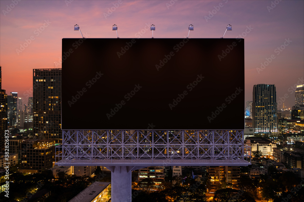 Blank black road billboard with Bangkok cityscape background at night time. Street advertising poster, mock up, 3D rendering. Front view. The concept of marketing communication to sell idea.