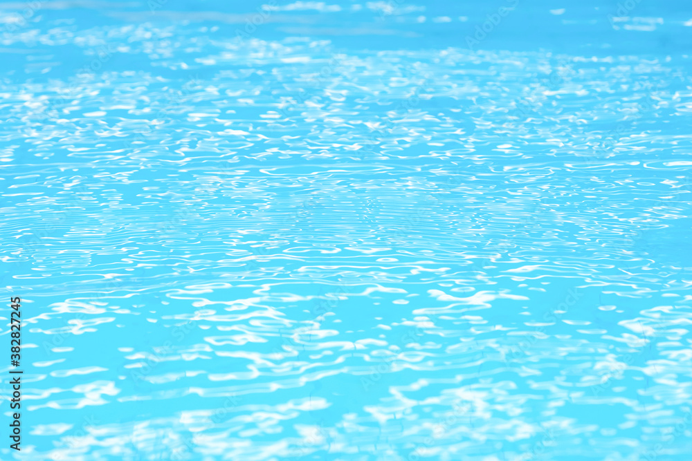 Abstract beautiful ripple wave water in swimming pool. Blue (turquoise) wave of water using as wallpaper or background. Blue water with sun reflection. Relaxation and refreshment concept