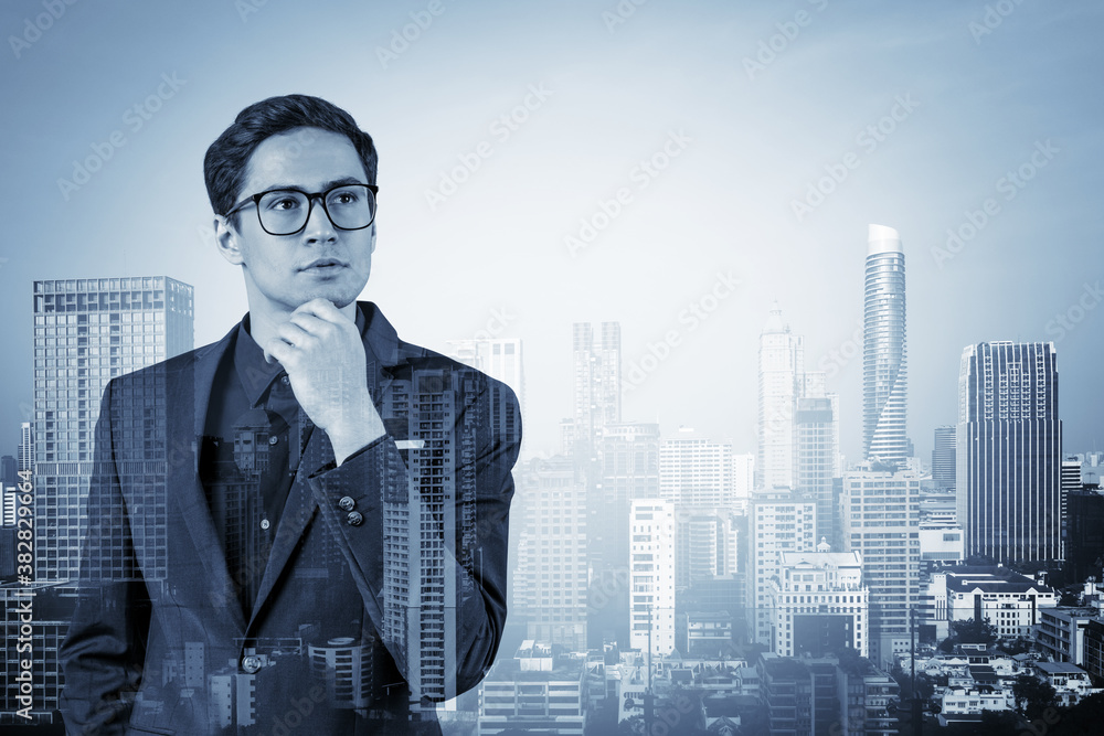 Young handsome businessman in suit and glasses dreaming about new career opportunities after MBA graduation. Bangkok on background. Double exposure. Young handsome businessman in suit and glasses dreaming about new career opportunities after MBA graduation. Bangkok on background. Double exposure.