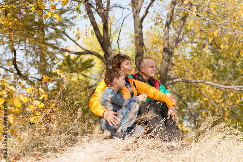 Fototapeta premium grandparents with their grandson spend time together in nature in the fall