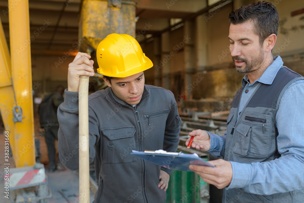 engineers discussing over clipboard at construction site engineers discussing over clipboard at construction site
