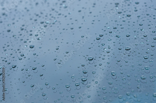 Rain water drops on the glass with a blue background.