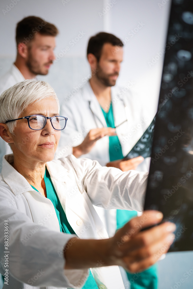 Doctors examining an x-ray report in hospital to make diagnosis Doctors examining an x-ray report in hospital to make diagnosis
