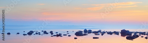 Rocks at the coast of Kasmu (captain's village) at sunset. Estonia, Baltic sea. Clear blue sky, pink clouds. Panoramic view. Travel destinations, vacations, eco tourism