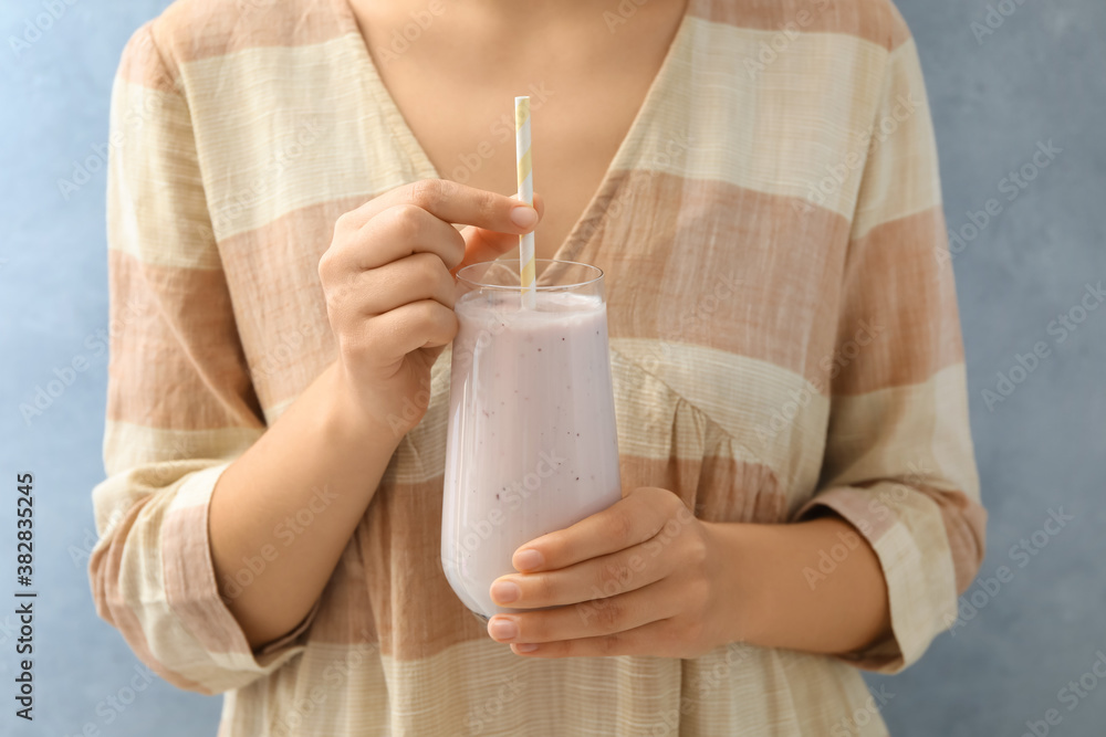 Woman holding fig smoothie on light blue background, closeup Woman holding fig smoothie on light blue background, closeup