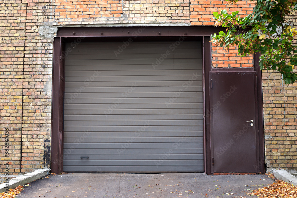 Automatic Electric Roll-up Gate Or Push-up Door. Shutter door or roller door and brick wall exterior. Brown Automatic shutters in a house. gates in the garage