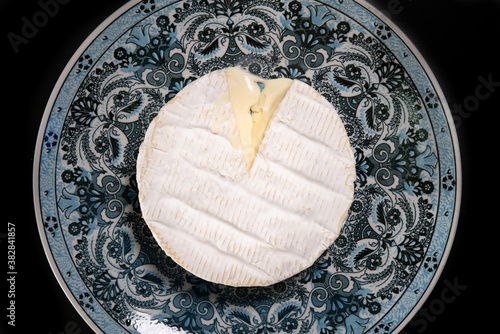 фотографія Coulommiers cheese in a decorated blue plate and black background