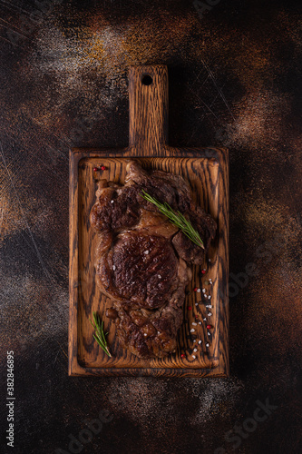 Grilled beef steak with spices on a wooden board.