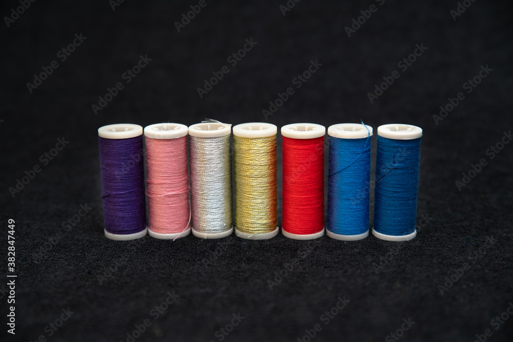 Spools of colorful sewing threads on a dark background Spools of colorful sewing threads on a dark background