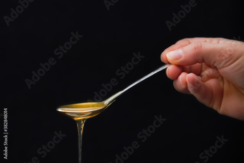 Spoon of liquid honey on black background