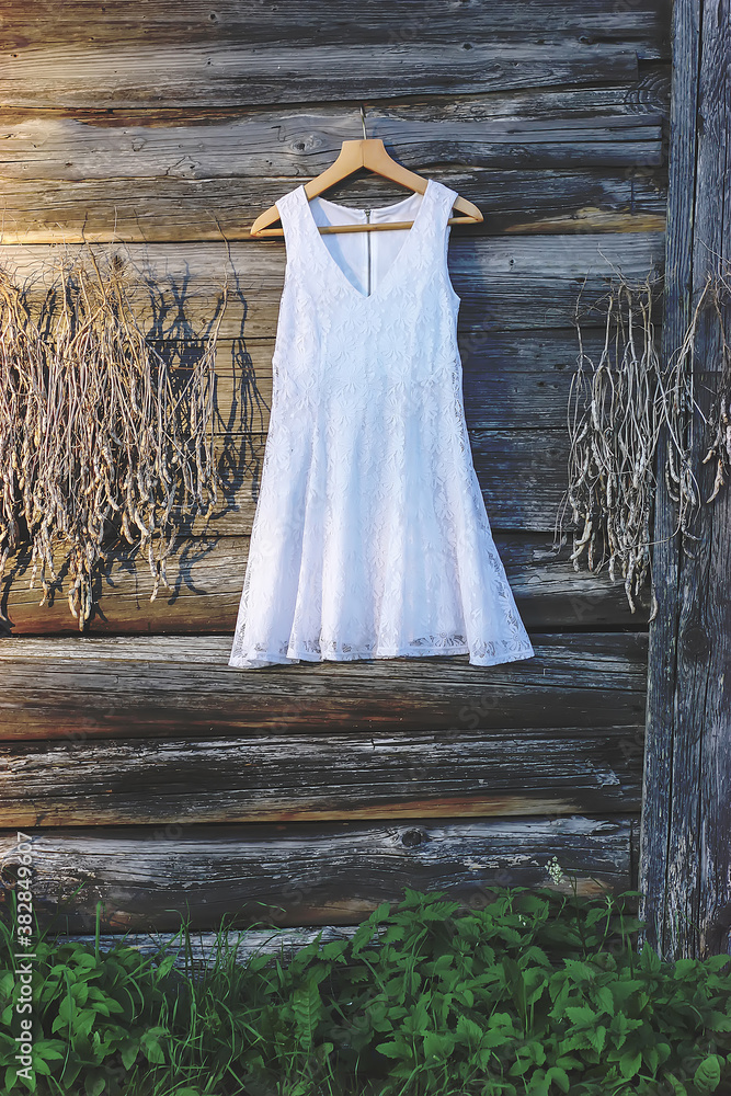 Linen white dress hanging on a hanger outdoors Linen white dress hanging on a hanger outdoors